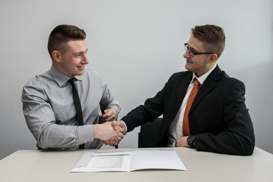 Two people shaking hands over a contract