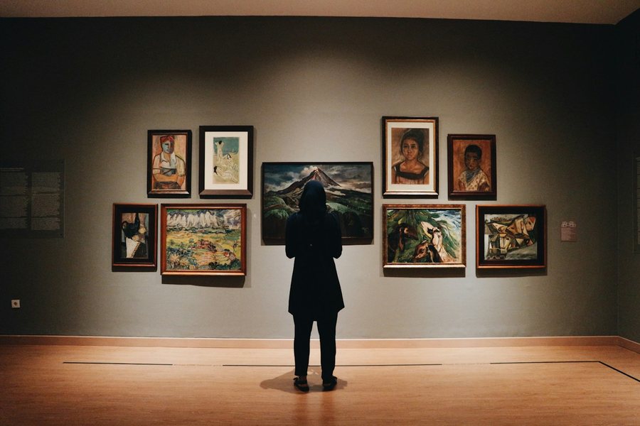 Visitor looking at paintings in a gallery